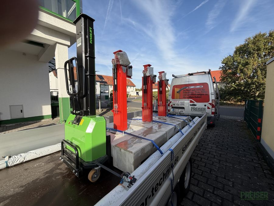 Verladen: Fertigfundamente, Hauptstützen und der Selbsteinladestapler auf dem Langgutanhänger, die 6-m-Schrankenbäume liegen daneben.